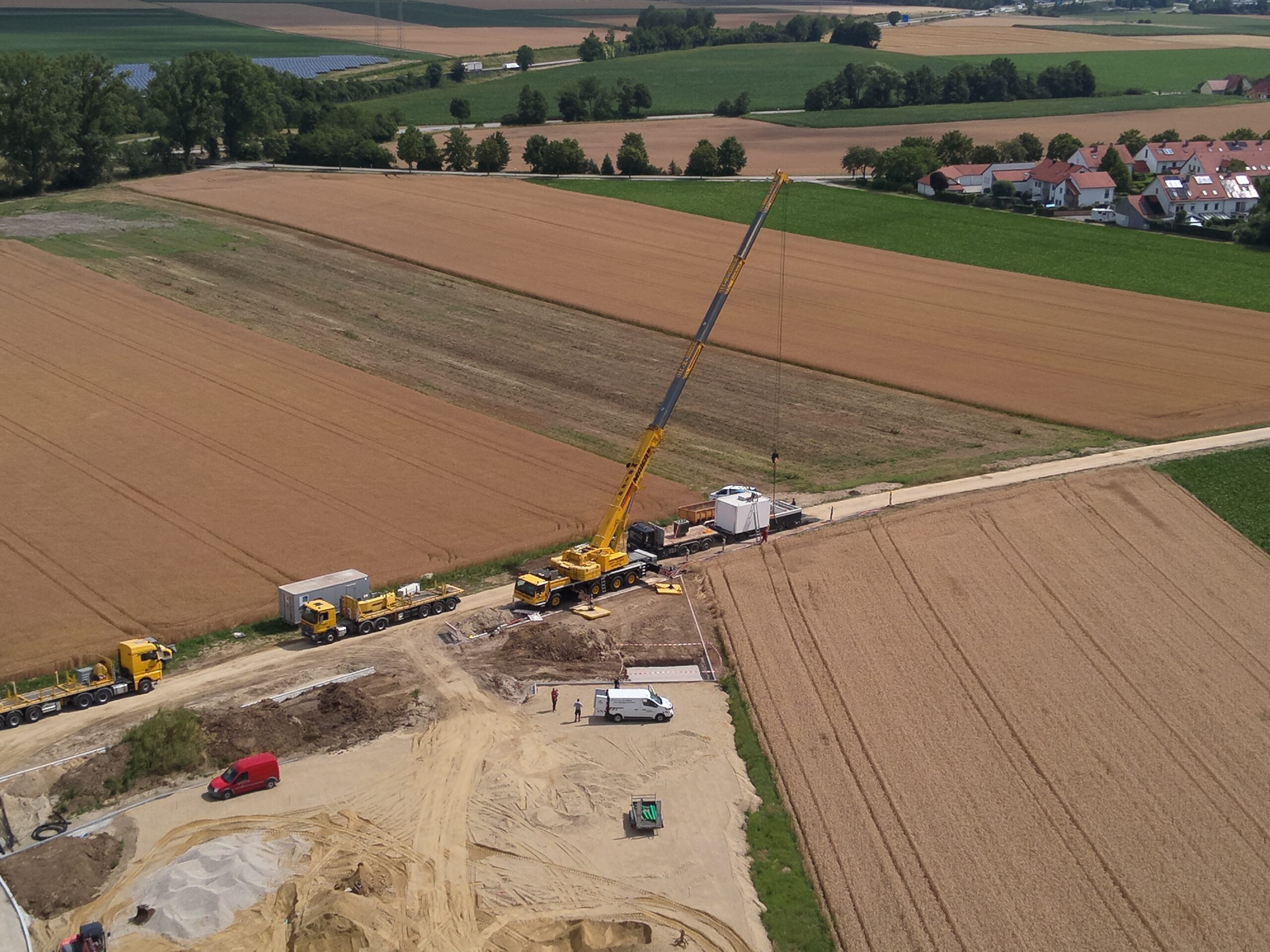 Luftaufnahme Baugebiet Schmidtfeld wie Kran die ÜZW Trafostation vom LKW hebt